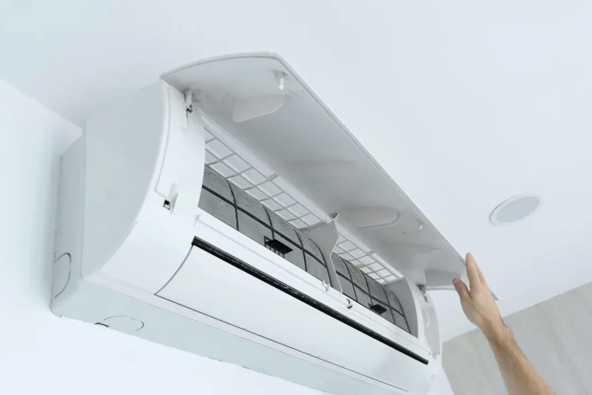 Hand opening the cover of a wall-mounted ductless air conditioner